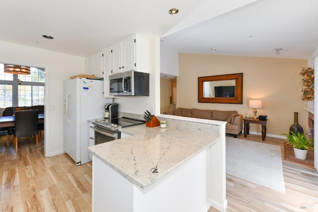 kitchen with a peninsula, appliances with stainless steel finishes, light wood finished floors, and vaulted ceiling