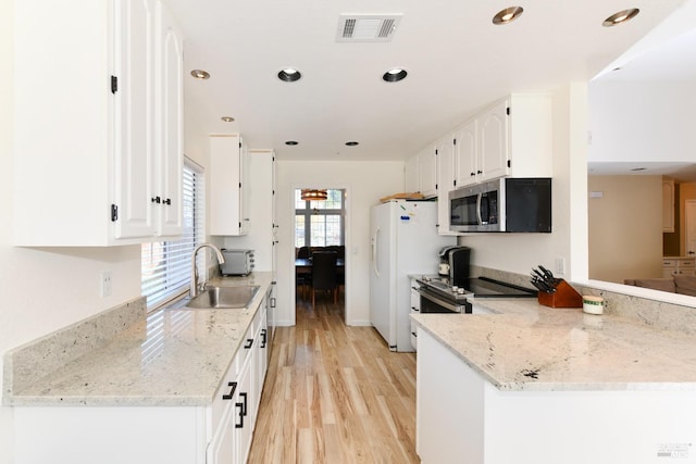 kitchen featuring light wood-type flooring, white cabinetry, visible vents, stainless steel appliances, and a sink