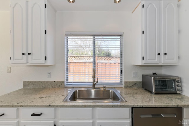 kitchen with a toaster, recessed lighting, white cabinetry, stainless steel dishwasher, and a sink