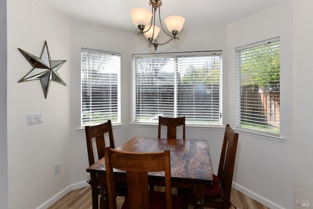 dining space featuring baseboards, light wood finished floors, plenty of natural light, and a notable chandelier