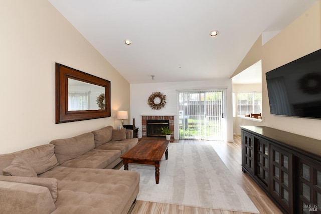 living area with recessed lighting, a brick fireplace, light wood-type flooring, and lofted ceiling