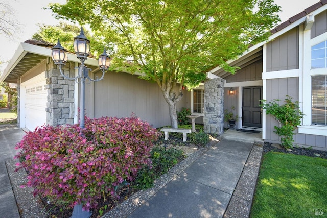 entrance to property featuring driveway, a garage, and stone siding