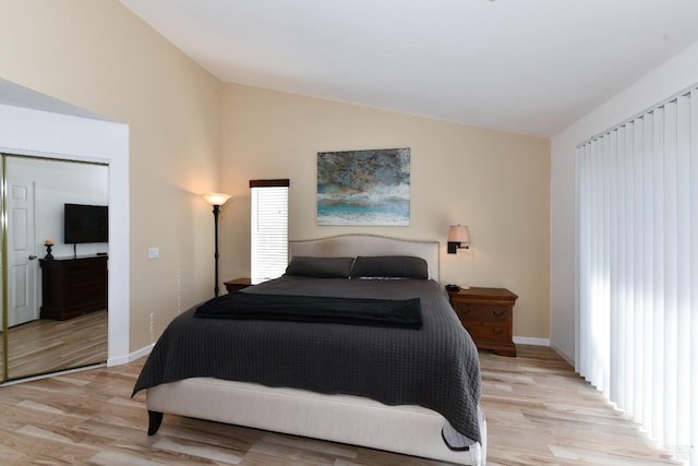 bedroom featuring light wood-style flooring, baseboards, and vaulted ceiling