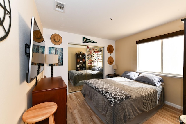 bedroom with visible vents, a closet, and wood finished floors