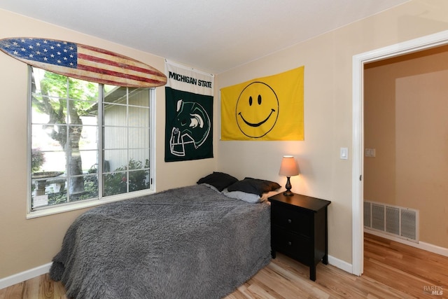 bedroom with visible vents, baseboards, and wood finished floors