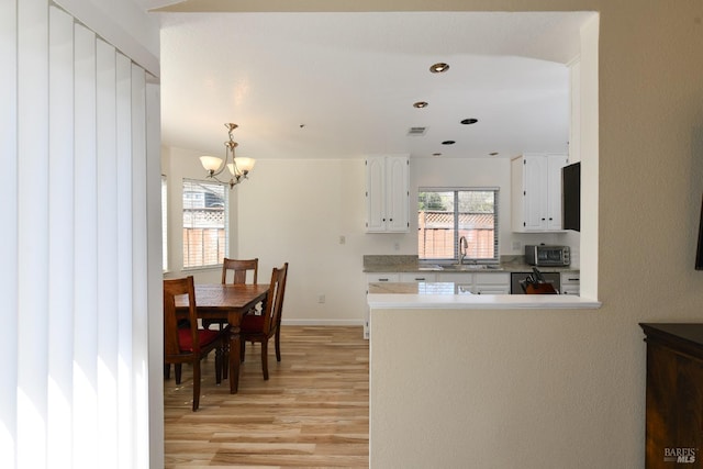kitchen with visible vents, a notable chandelier, a sink, white cabinetry, and light wood-style flooring