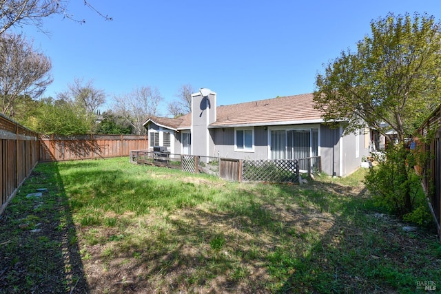 rear view of house with a yard, a fenced backyard, and a chimney