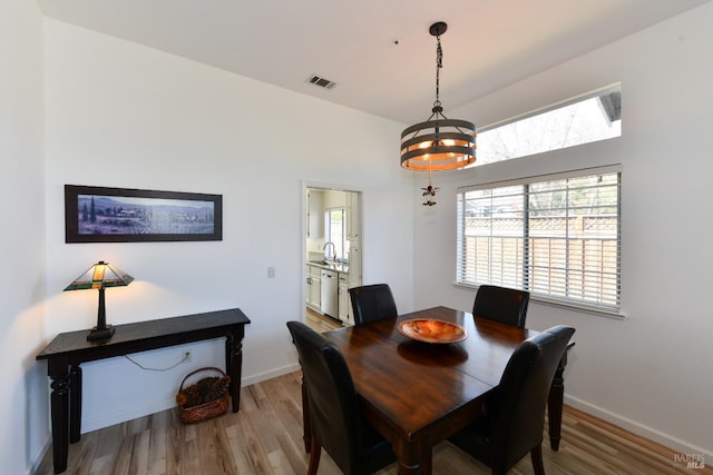 dining area featuring a chandelier, light wood finished floors, visible vents, and baseboards