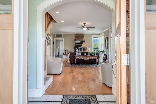 corridor featuring recessed lighting, crown molding, visible vents, arched walkways, and light wood finished floors