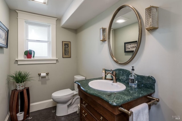bathroom featuring tile patterned flooring, vanity, baseboards, and toilet