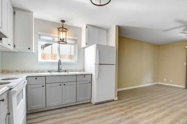 kitchen with white appliances, light wood-style flooring, a sink, hanging light fixtures, and gray cabinetry