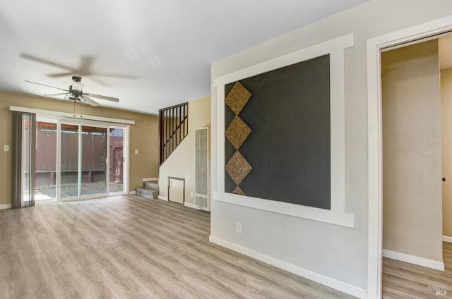 unfurnished living room featuring ceiling fan, stairway, wood finished floors, and baseboards