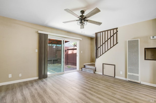 unfurnished living room with stairway, a heating unit, a ceiling fan, and wood finished floors