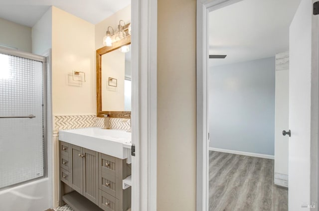 bathroom with combined bath / shower with glass door, vanity, and wood finished floors