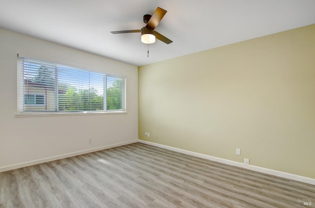 unfurnished room featuring baseboards, light wood finished floors, and a ceiling fan