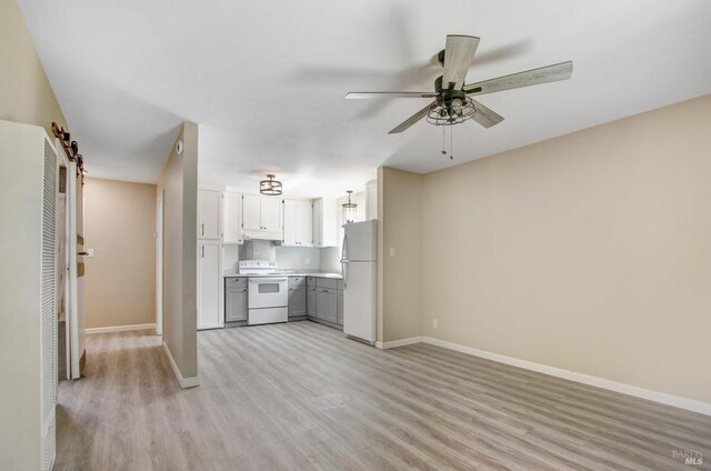 unfurnished living room with light wood-type flooring, baseboards, and a ceiling fan