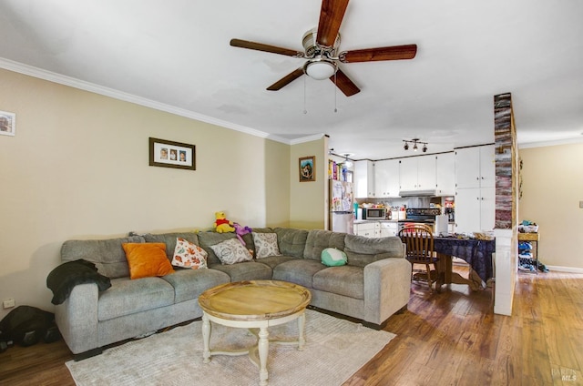 living room featuring baseboards, a ceiling fan, ornamental molding, and wood finished floors