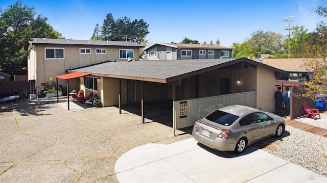 view of front of home featuring a carport, concrete driveway, and roof with shingles