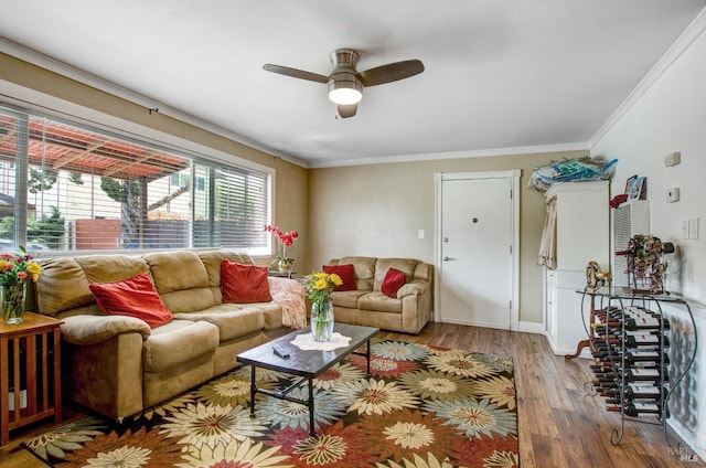 living area featuring baseboards, wood finished floors, ornamental molding, and ceiling fan