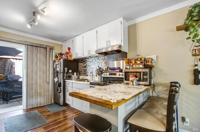 kitchen with backsplash, white cabinets, under cabinet range hood, dark wood-type flooring, and stainless steel appliances