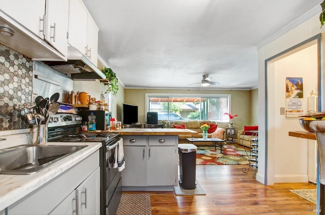 kitchen with open floor plan, light countertops, stainless steel electric stove, light wood-style floors, and under cabinet range hood