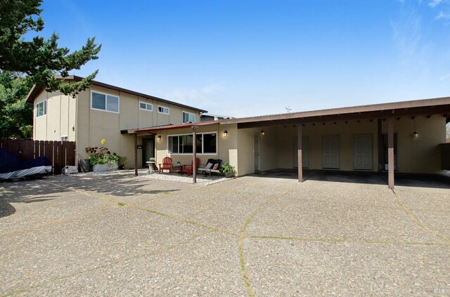 view of front of home featuring fence, stucco siding, and an attached carport