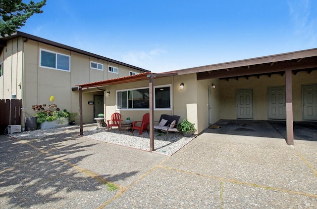 view of front of property with an attached carport, a patio area, and stucco siding