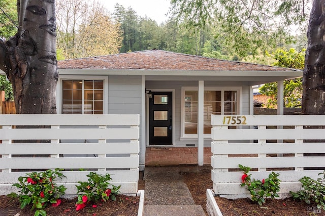 exterior space featuring a shingled roof and a fenced front yard