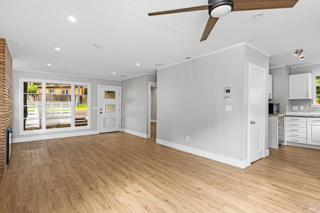 unfurnished living room with light wood-style floors, baseboards, ornamental molding, and a ceiling fan