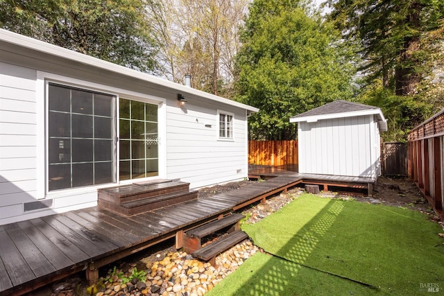 deck with a fenced backyard, an outdoor structure, and a lawn