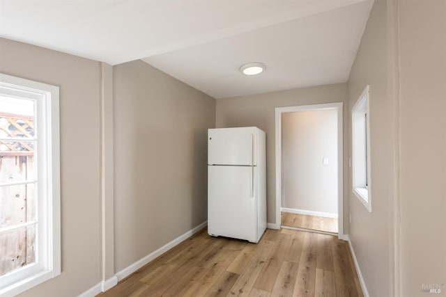 kitchen featuring light wood-style flooring, freestanding refrigerator, and baseboards