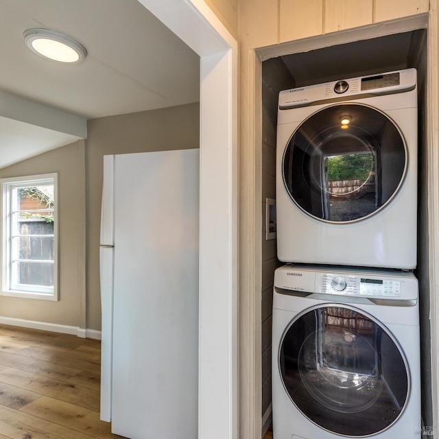 laundry area with laundry area, baseboards, hardwood / wood-style flooring, and stacked washer / drying machine