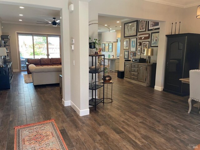 corridor featuring dark wood finished floors, baseboards, ornamental molding, and recessed lighting