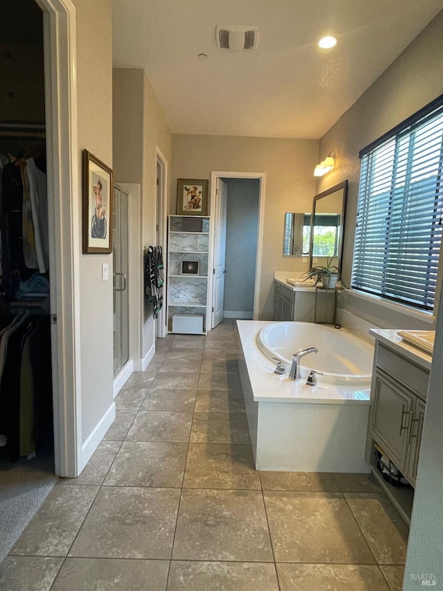 full bath with visible vents, a bath, a spacious closet, vanity, and a stall shower