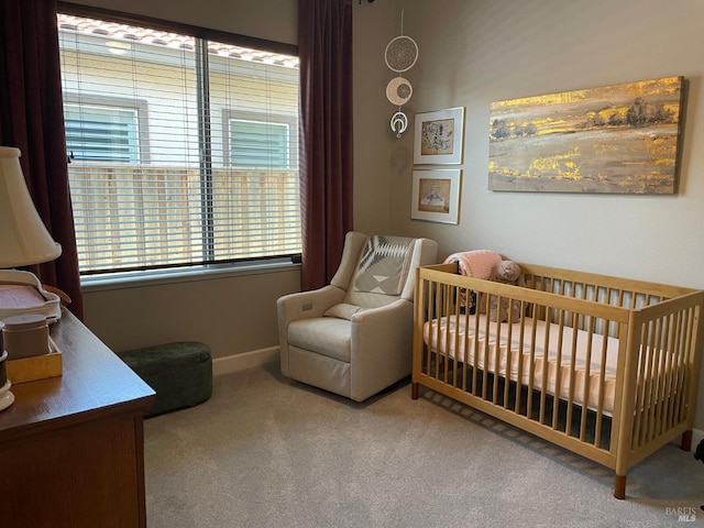 bedroom with a nursery area, baseboards, and carpet flooring