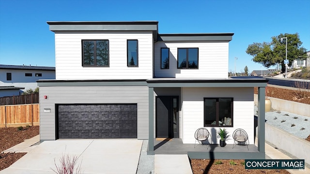 view of front of house with concrete driveway, a garage, and fence