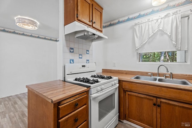26228 Otter Dr, Willits, CA 95490 - kitchen featuring white gas stove, under cabinet range hood, brown cabinetry, light wood finished floors, and a sink