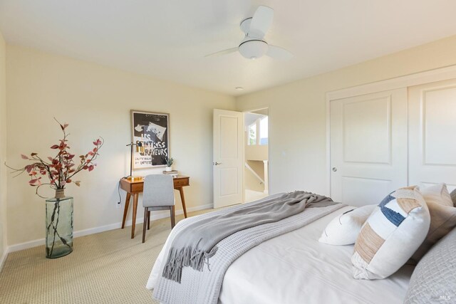 bedroom featuring a closet, baseboards, ceiling fan, and light carpet