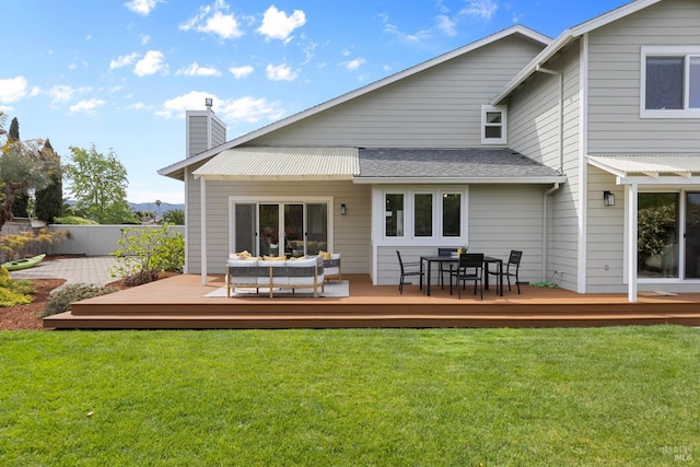 rear view of property with a chimney, a deck, and a lawn