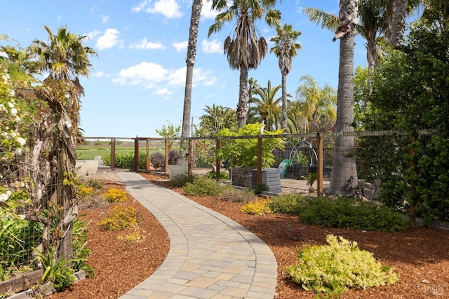 view of property's community with fence and a vegetable garden