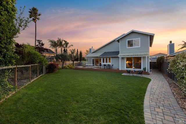 back of property with a yard, a fenced backyard, and a wooden deck
