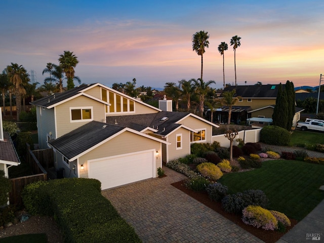 view of front of house featuring a shingled roof, a front lawn, decorative driveway, and an attached garage