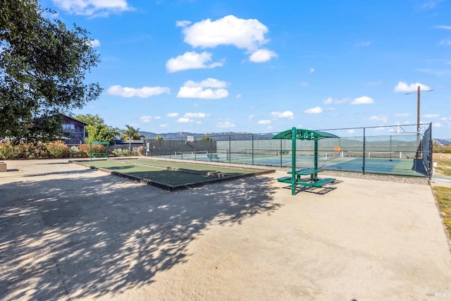 view of property's community featuring fence and a tennis court