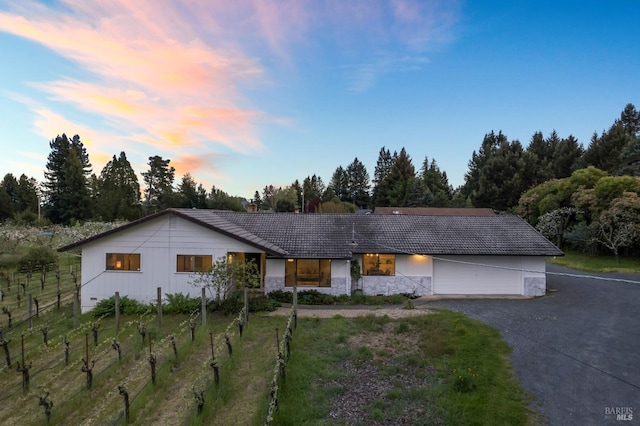 single story home featuring driveway, stone siding, a garage, a tiled roof, and fence