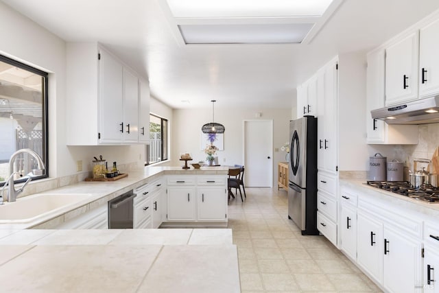 kitchen featuring a peninsula, white cabinetry, under cabinet range hood, appliances with stainless steel finishes, and a sink