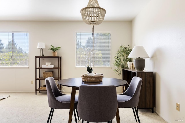 dining room with light carpet, an inviting chandelier, and baseboards