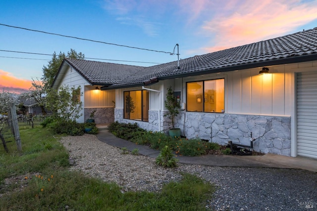 exterior space with board and batten siding and a tiled roof