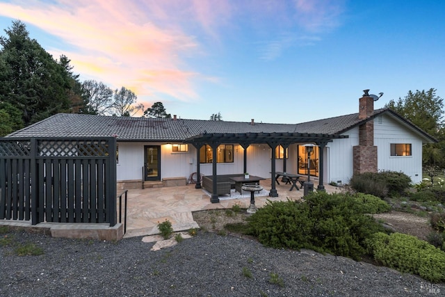 rear view of property featuring a pergola, a patio area, a chimney, and a tile roof