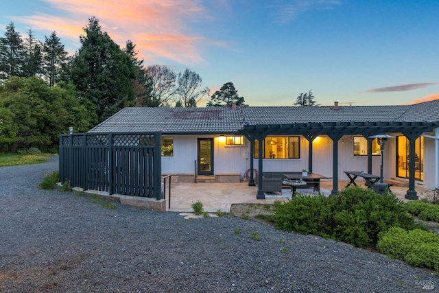 rear view of property with a patio area, a tile roof, and board and batten siding
