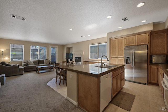 kitchen featuring visible vents, stainless steel fridge, dishwasher, a sink, and dark countertops